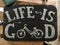 White inscription Life is good on an old wooden black board with a bicycle