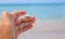 White insect on a man`s hand against the background of the sea.