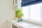 White interior background, close-up abstract details, table, roman blinds, window, blue flowerpots