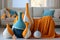 White interior, couch with orange blanket, light blue pillows and vases