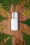 White IQOS battery  with  individual sticks lies on decorative abstract wooden texture with green and yellow leaves of fern