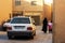 A white Iranian-made car drives through the old city`s narrow street. A woman in chador takes the children to school