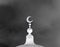 White Islamic symbol on mosque cupola on dark clouds