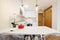 White island table in a kitchen with metal and transparent methacrylate chairs, an open kitchen with white furniture and built-in