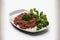 On a white, isolated dish, there is minced beef and parsley leaves