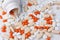 White jar with different pills spilling out on white background. Spilled orange and white pills