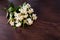 White Jasmine flowers with green leaves on dark brown wooden table. Flat lay, top view, copy space for text. Floral wallpaper