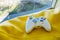 White joystick for game console on a bright yellow background near the window