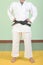 White judo gi. A young martial arts master knots a black belt.
