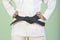White judo gi. A young martial arts master knots a black belt.