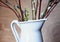 white jug branch buds leaves wood background