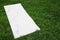 White karemat or fitness mat on green grass outdoors. Space for text