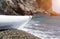 White kayak on an isolated pebble beach against the backdrop of rocks in the sea. Copy space. The concept of travel