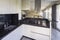 White kitchen with black marble top and large hood