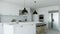 White kitchen interior with island, kitchen appliances and lighting.