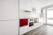 White kitchen with red touches prepared to release with an exit door to a shop terrace with appliances