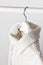 White knitted wool sweater on a white wooden hanger against the background of the light wall. Autumn and winter clothes. Store con