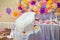 White lace cradle, balloons, candy bar, white candles and flower petals on the table. Paper multicolored flowers