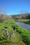 A white lady bike on a riverside. Bicycle with a little bag in the nature, creek and woods around