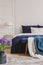 White lamp on stylish golden nightstand table next to king size bed with navy blue bedding