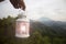 White lantern in hand on a mountains background. Morning view. Person carry lantern with candle light inside on mountain.