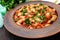 White large beans in sweet and sour tomato sauce in a clay bowl on a dark background. Vegetarian cuisine. Lenten meal.
