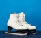 White leather skates for figure skating stand on a blue wooden background