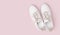 White leather sneakers with laces isolated on pink background