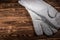 White leather welder gloves on a wooden background. A studio photo with hard lighting