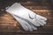 White leather welder gloves on a wooden background. A studio photo with hard lighting