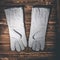 White leather welder gloves on a wooden background. A studio photo with hard lighting