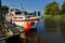 white leisure boat in the canal Abser Sieltief during high tide on a sunny summer day with blue sky