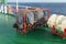 White life raft and embarkation ladder on deck of container ship ready to use in emergency situation.