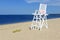 White lifeguard chair on empty sand beach with blue sky