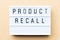 White light box with word product recall on wood background