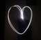 White light from a flashlight draws a heart at night.