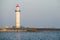 White lighthouse located on a seaside on sunny day. Symbol of in