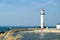 White lighthouse located on a seaside on sunny day. Symbol of in