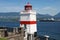 A white lighthouse with a red stripe at Brockton Point on the seawall in Vancouver, British Columbia.