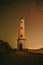 A white lighthouse with a sky filled with stars as a background