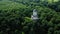 White little church around green dense forest. Aerial view from drone.