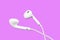 White little headphones isolated on purple background. Earphones isolated on black background.