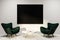 White living room, green armchairs, black poster