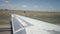 White, long wing airplane moving along runway. Tractor, field on background