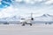 White luxury executive aircraft taxiing on airport taxiway in winter on the background of high scenic snow capped mountains