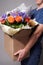 White male courier holding a large box with several bouquets. Delivery concept.