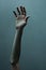 a white man hand and arm reaching up for help. dark teal background wall texture. reaching out to help. Helping hand.
