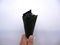 A white man holds a black nibbled ice cream in a black waffle cone with a white paper napkin on a cloudy summer day