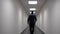 White man walks down the long white corridor. Blurred background. Video contains flicker and noise.