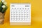 White March 2023 calendar with potted plant on yellow background.